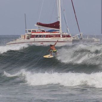 Man surfing next to Catamaran